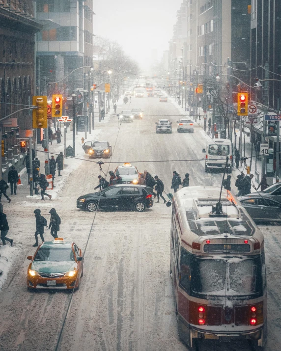 many cars are driving on a city street in the snow