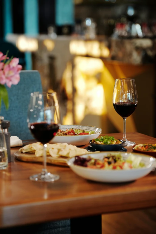 a dining room with many dishes of food and glass of wine