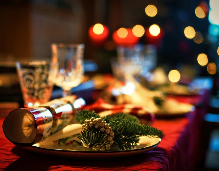 a plate with a christmas decoration next to candles and wine glasses