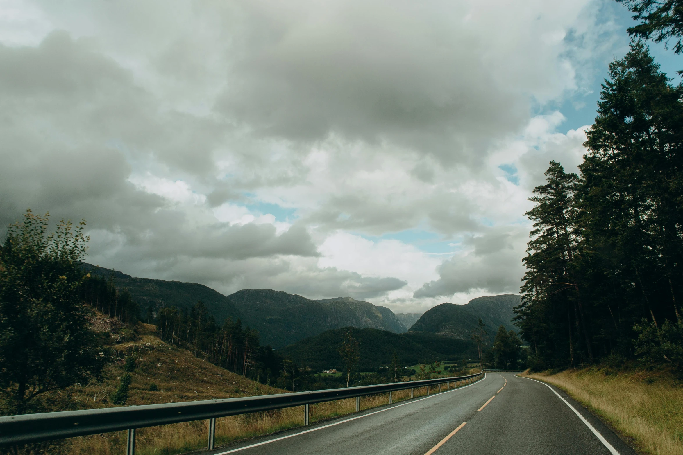 a road that has trees and mountains along side it