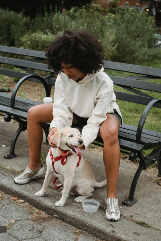 a woman is sitting on the bench with her dog