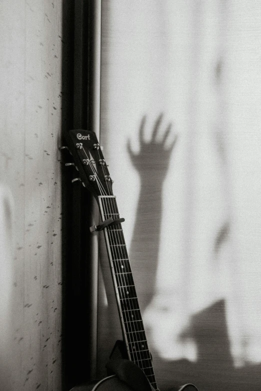 black and white po of an acoustic guitar with shadow on the wall