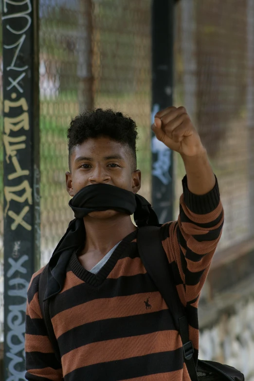 a young man stands and raises his fist