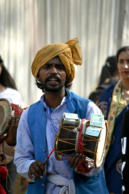 a man holding two drum drums and singing into a microphone