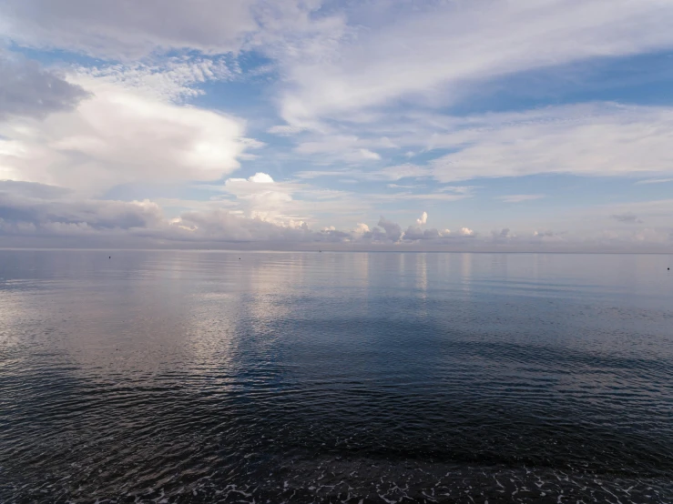 the calm blue sky is reflected on the still water