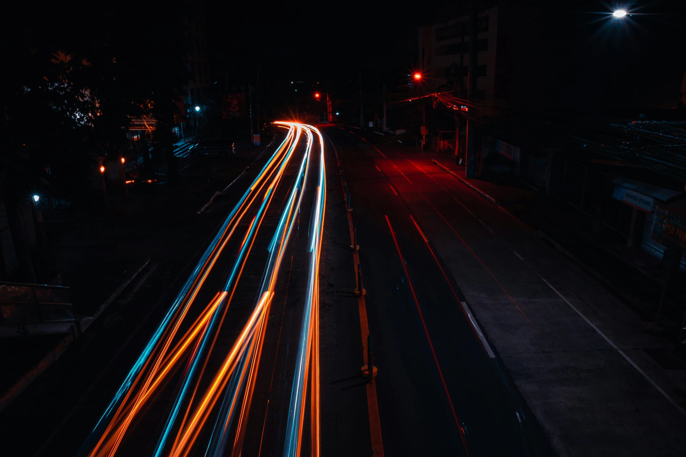 a line of traffic traveling past a street sign at night