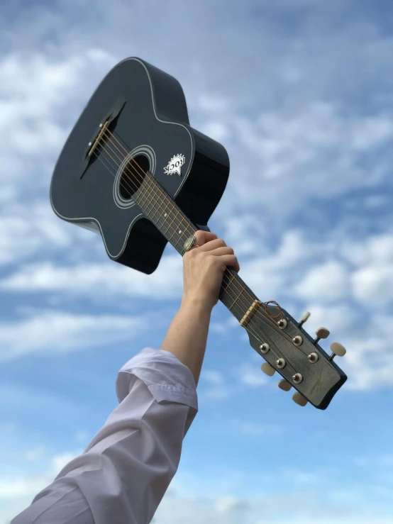 a man holding onto an old guitar with blue sky background