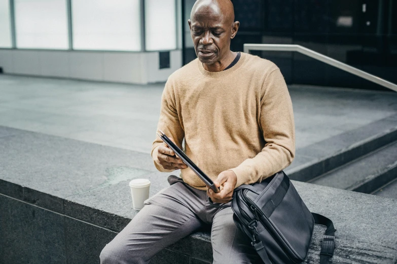 man sitting down next to a coffee cup and a bag