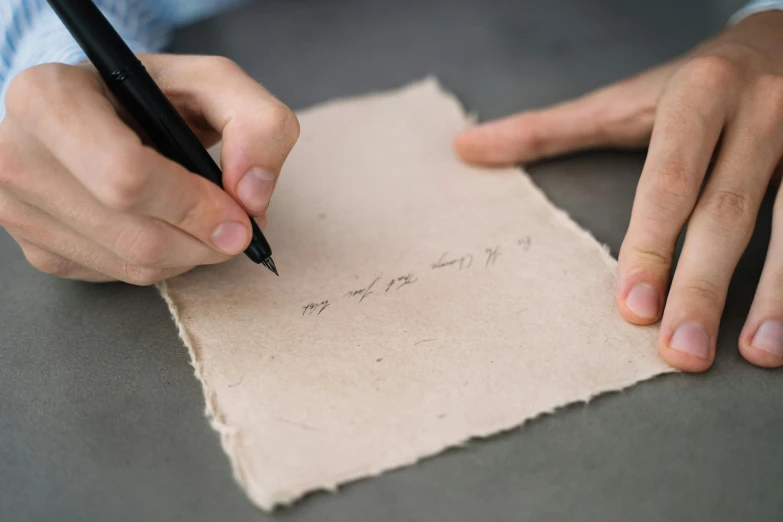 a person writing on a piece of paper with their hands