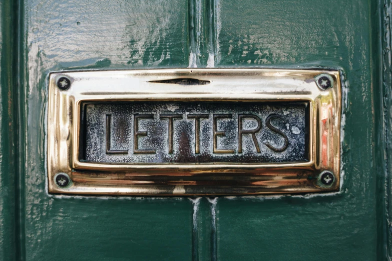 an old metal sign on a green door that reads letters