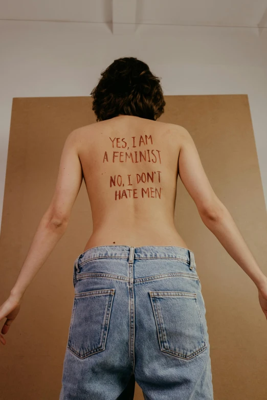 a young woman with her back turned looking down has some writing written on the bottom of her body