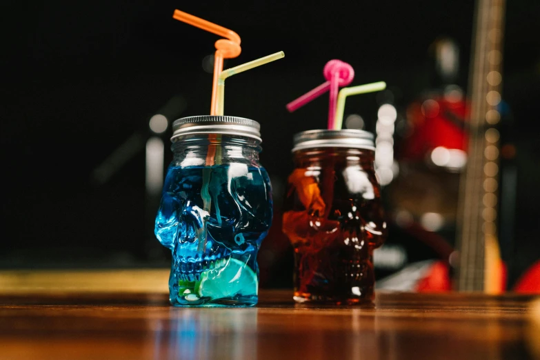 two jars are holding colorful straws on a table