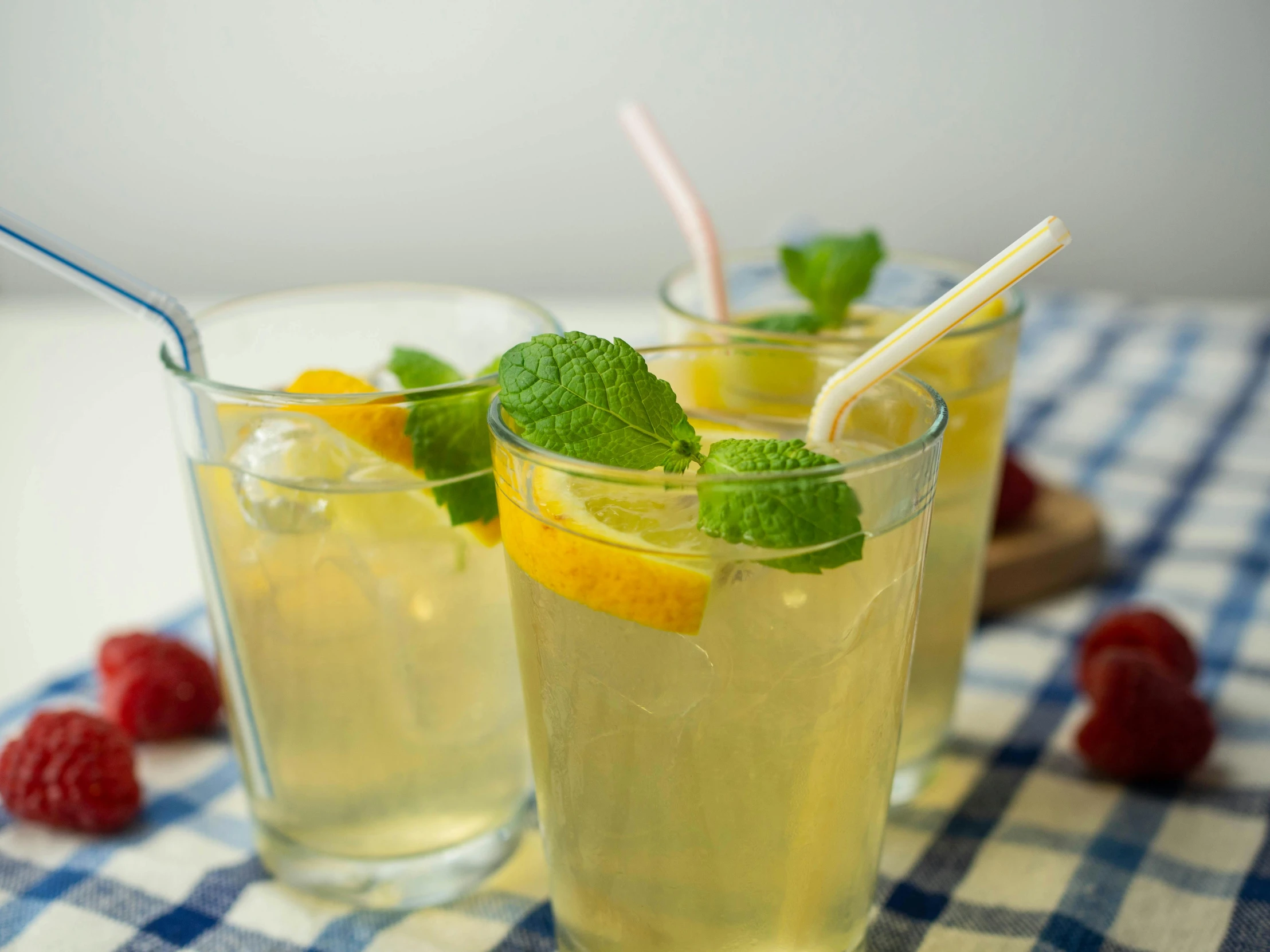 two glasses filled with some lemonade and limeade on a blue checked cloth