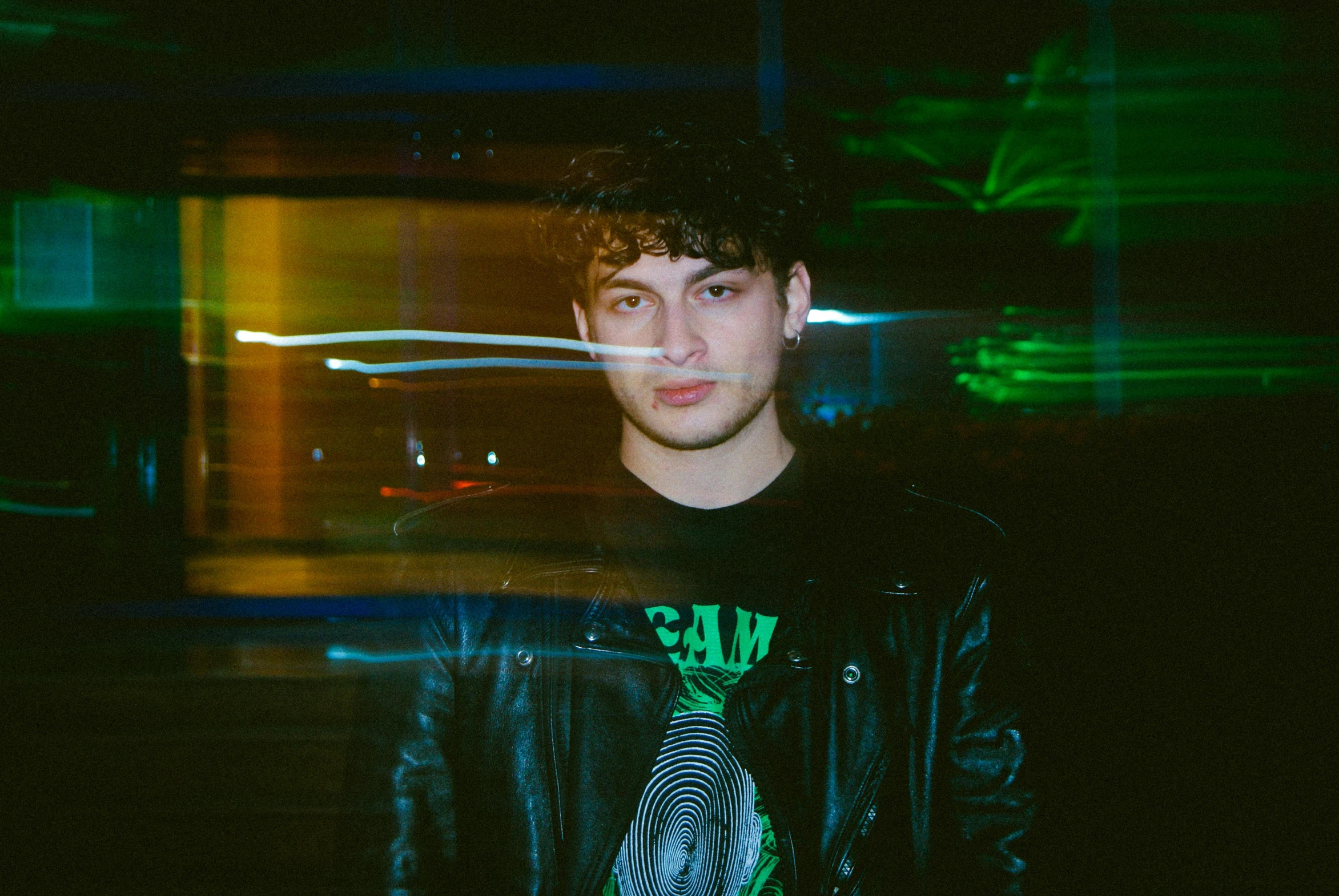 young man in black leather jacket standing next to building