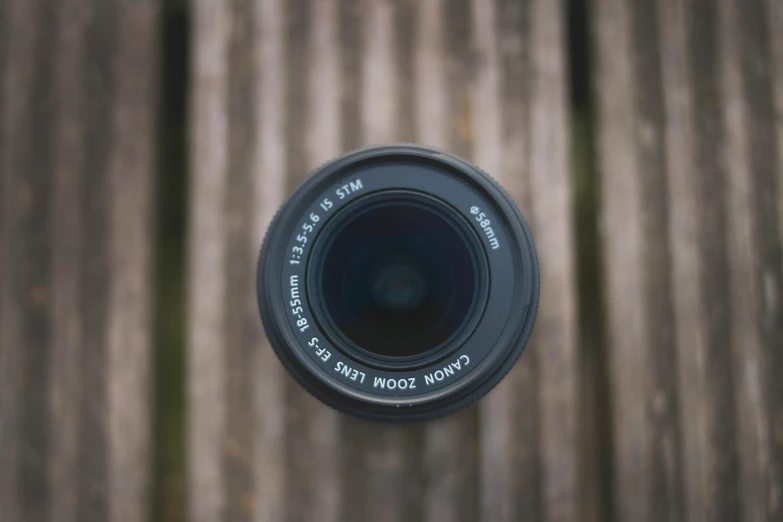 a black camera lens laying on a wood surface