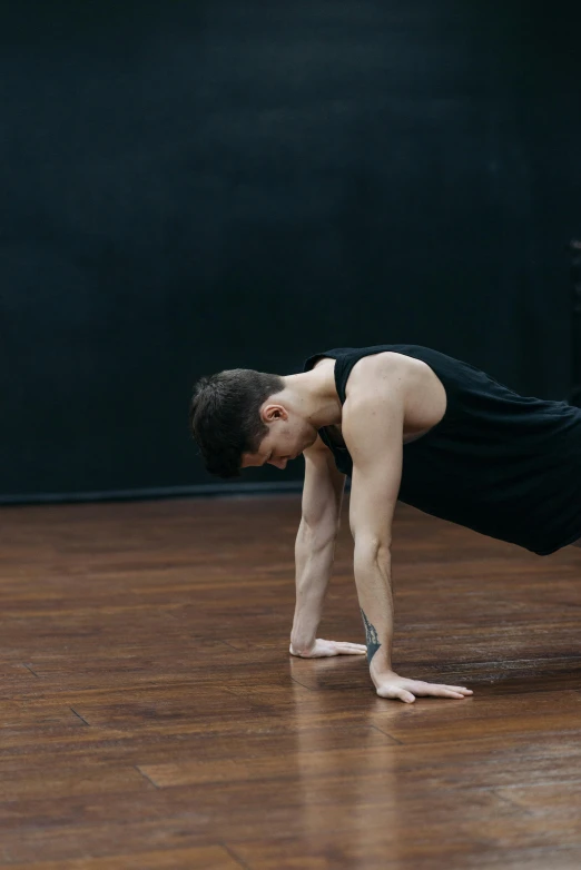 man in black doing handstand on wooden floor