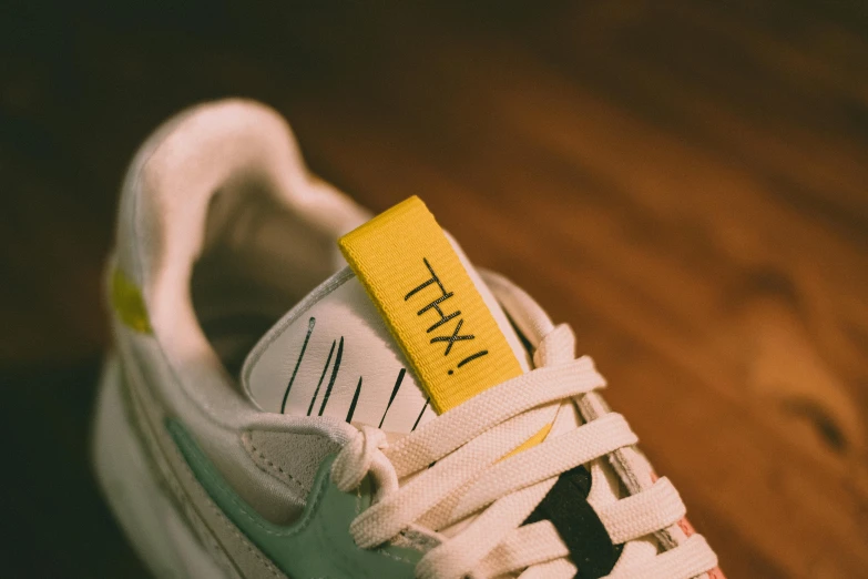 a person in sneakers with a yellow tag on their shoe
