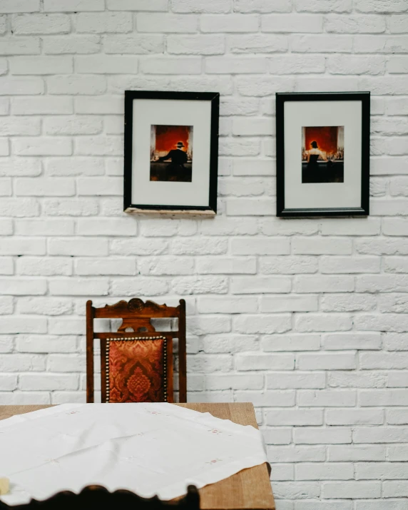 a white brick wall is decorated with two pictures