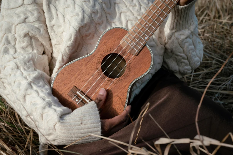 a person sitting in the grass with an ukulele