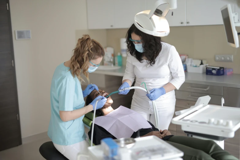 two dentists examining a patient while standing in an operating room