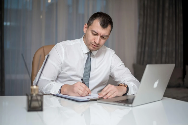 a man wearing a tie and a shirt is looking at soing on his laptop