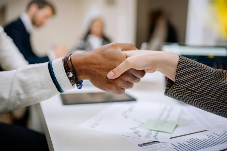 two people standing at a table shaking hands