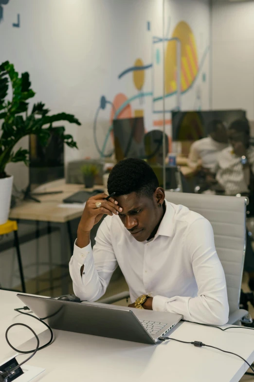 a man sitting at his desk, talking on the phone and working