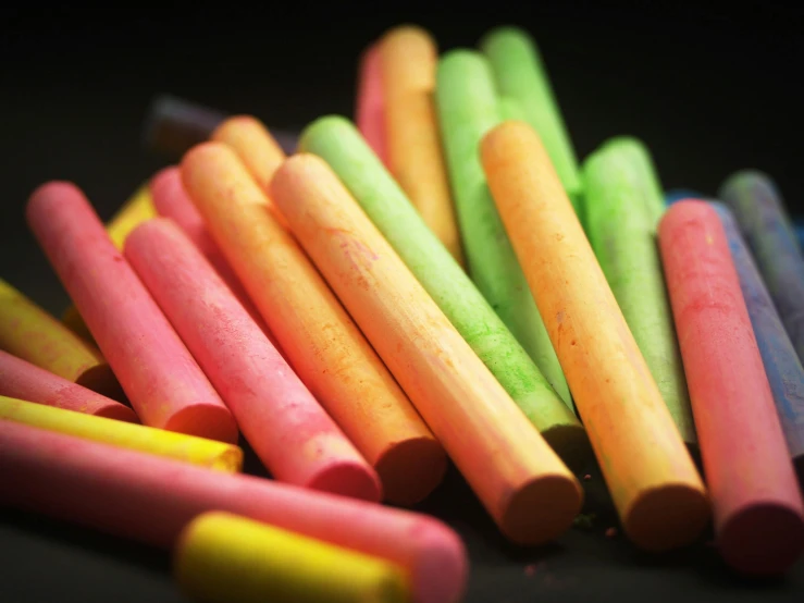 a bunch of colored crayons that are on a black surface