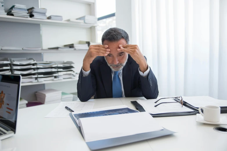 the man sits at a desk with paperwork in front of his