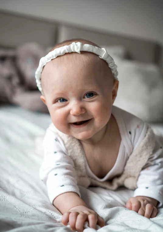 a baby wearing a white outfit laying on top of a bed