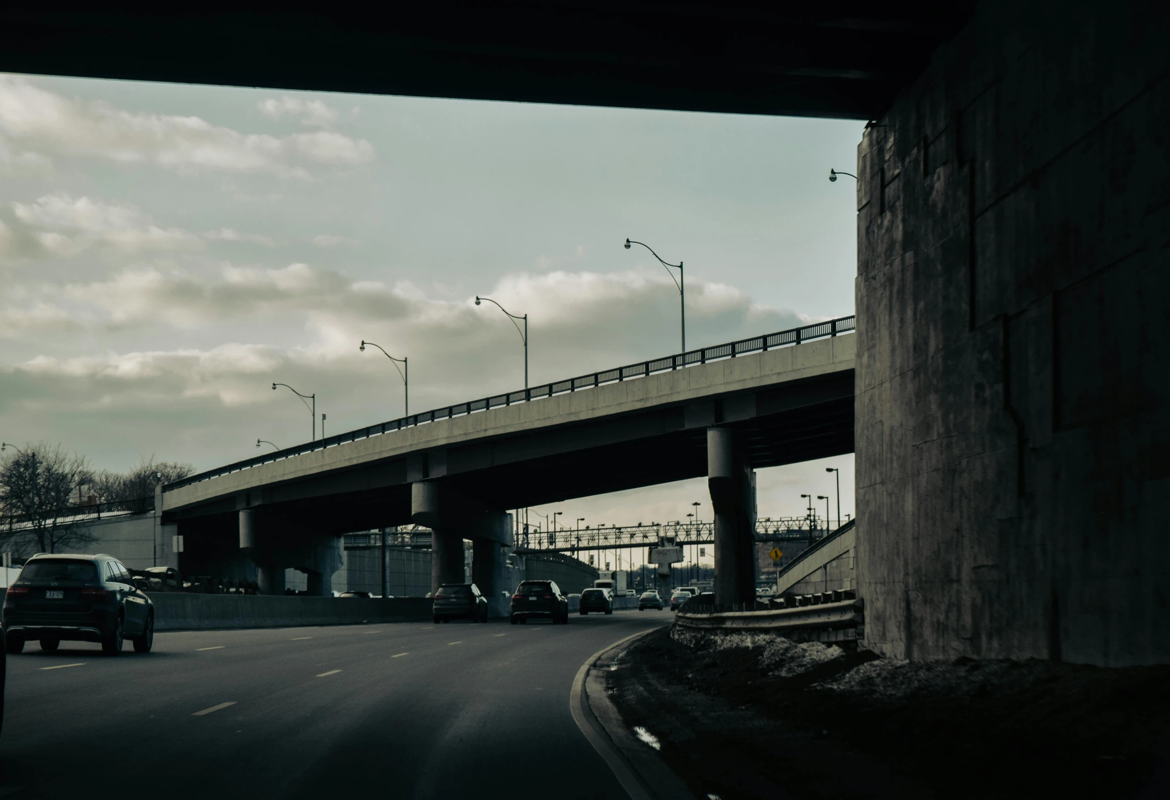 cars driving on road beneath a large bridge