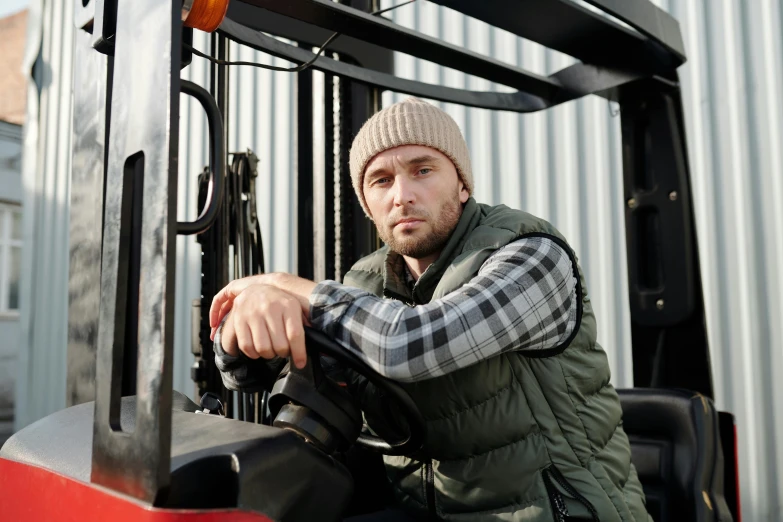 a man sitting on a forklift with his hands on the rim