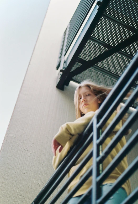 a woman in a yellow sweater standing on a stairs