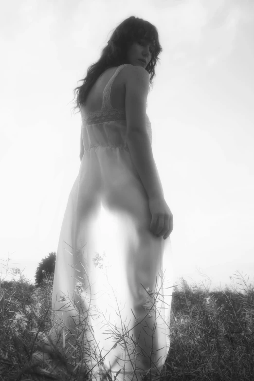 a  woman in a high - slit is standing in an open field