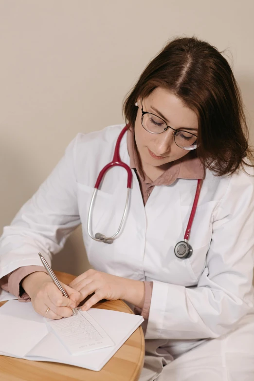 a female doctor is at a table writing soing