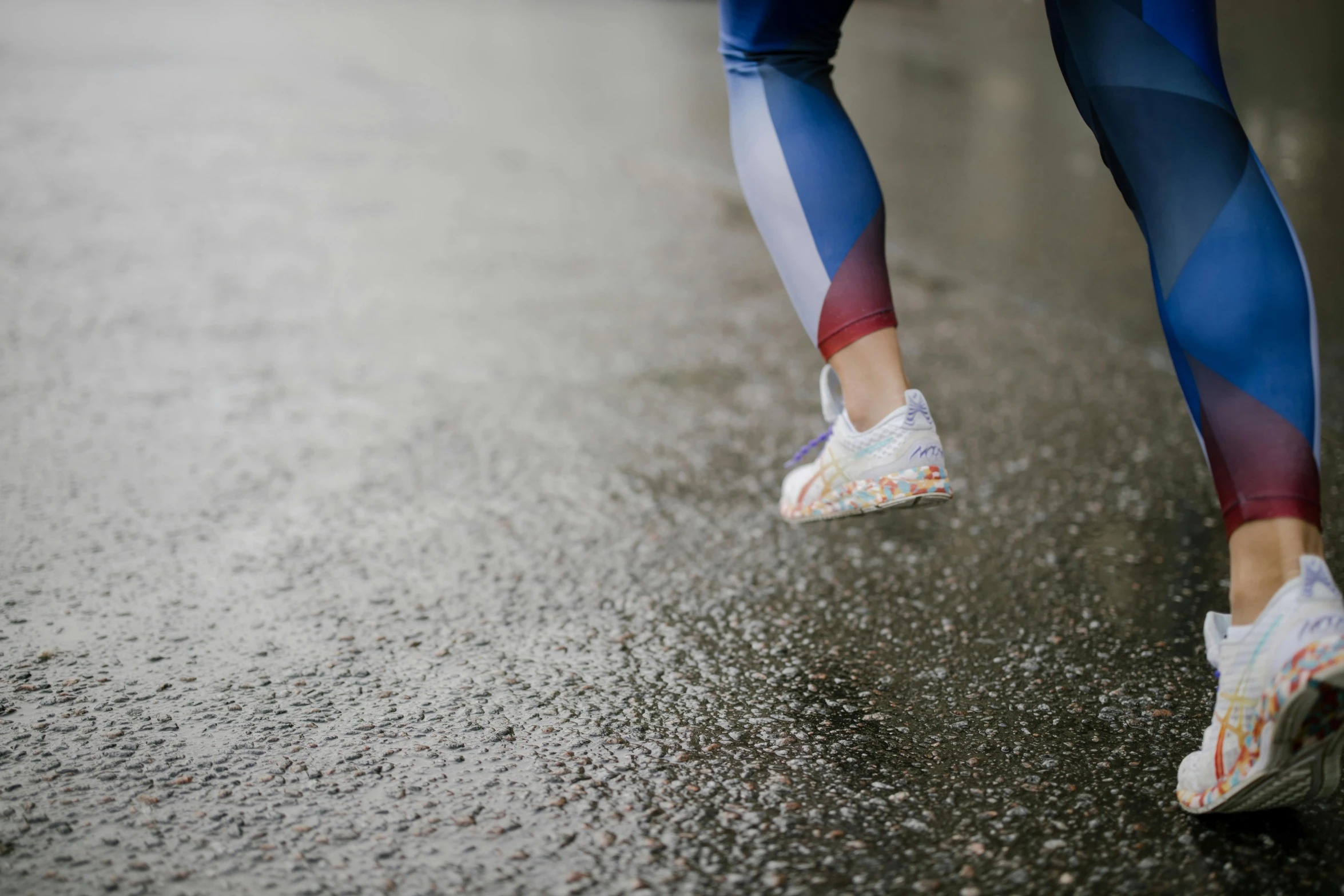 a woman's legs in running shoes are reflected in the wet asphalt