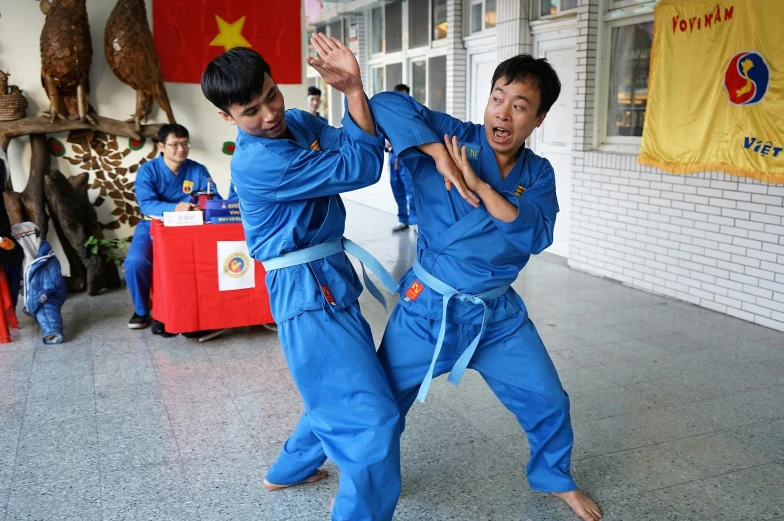 two boys wearing blue karate uniforms performing martial moves