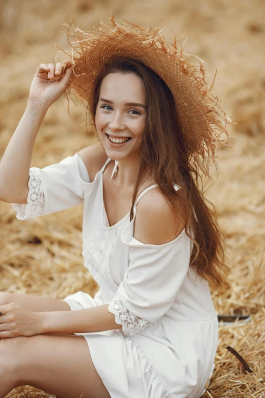 a young lady in white is posing on hay