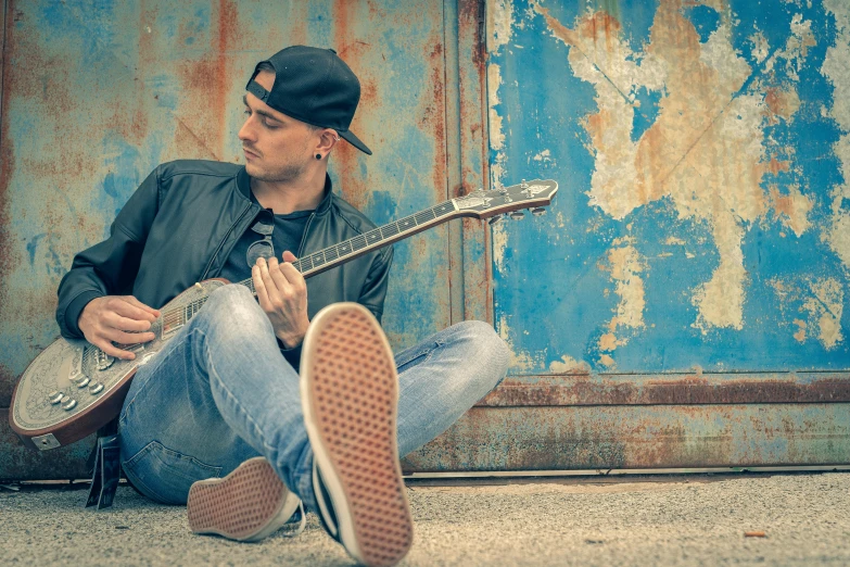 the man is playing guitar near the wall