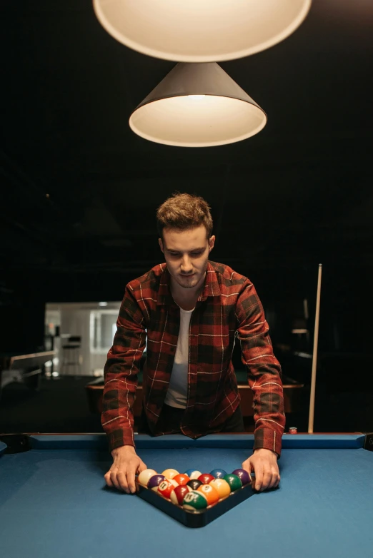 a man with glasses and a jacket leaning over a pool table