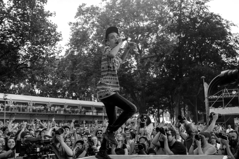 man on stage with camera around feet in front of large audience