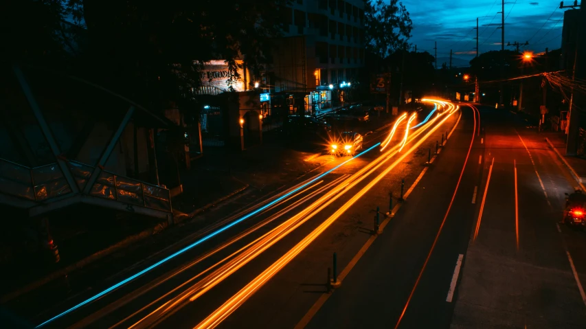 cars streak down a city street at night