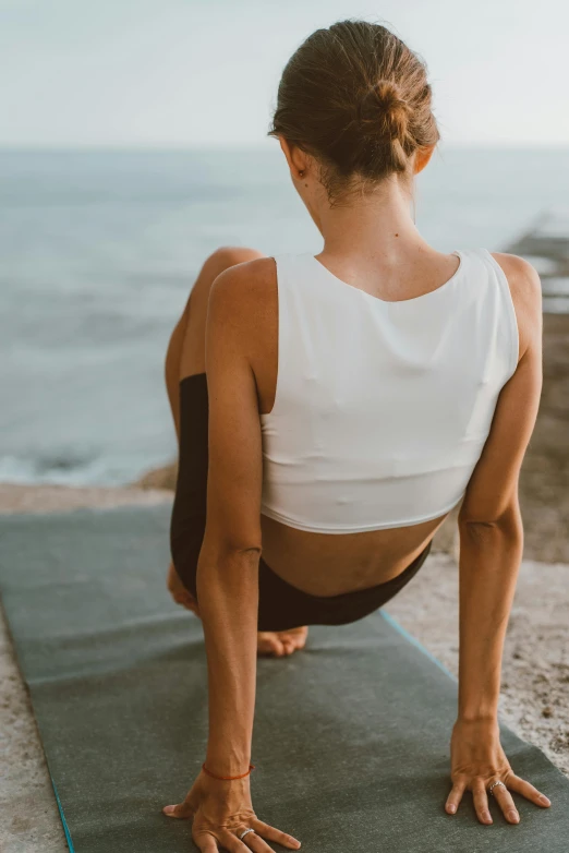 a woman in a yoga outfit doing a back - bend pose by the beach