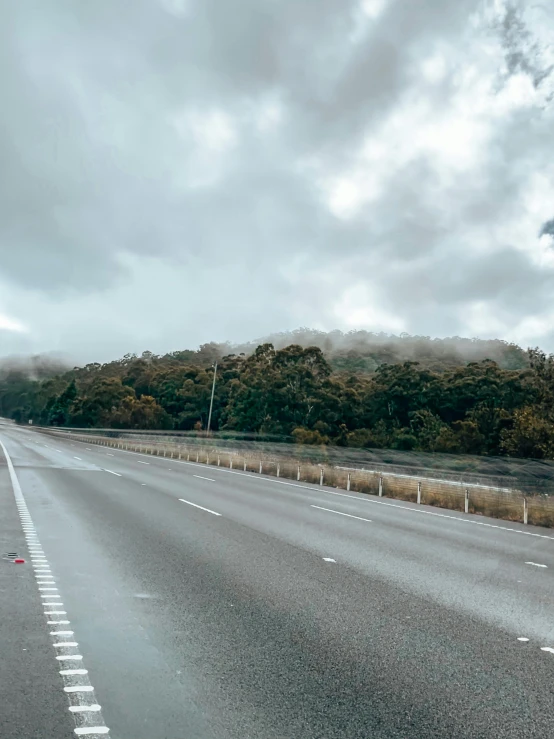 a deserted highway with fog on the trees