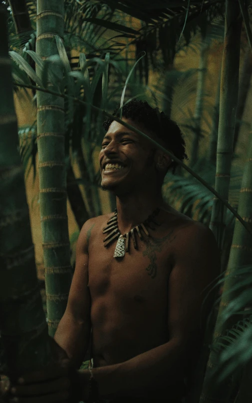 man wearing tribal headdress standing in front of plants