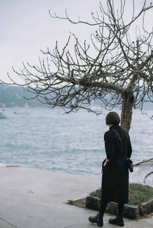 a man dressed in all black looking out at the water