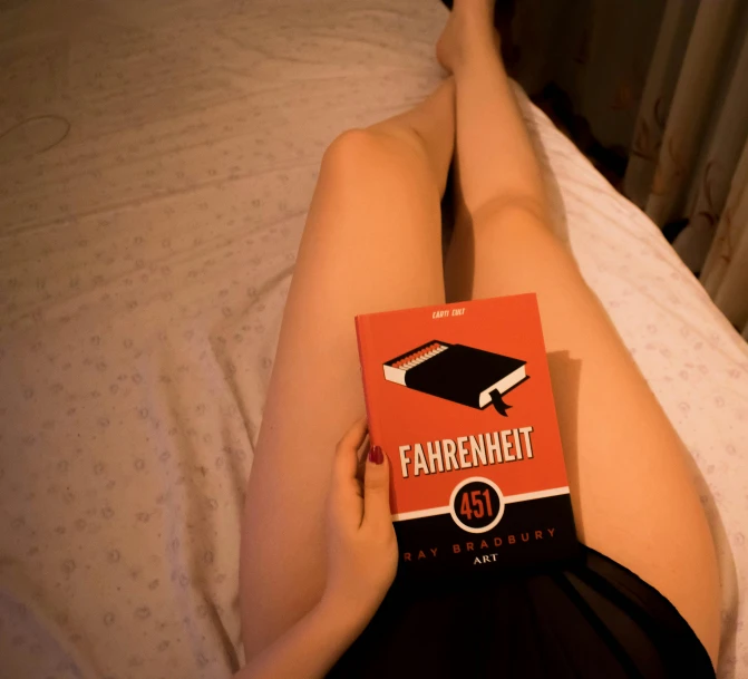 a woman laying in bed holding an orange box