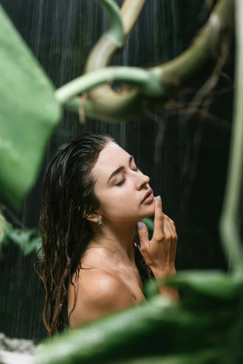 a young woman brushing her face under a shower head