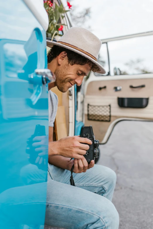a man holding a camera sitting on the side of a vehicle