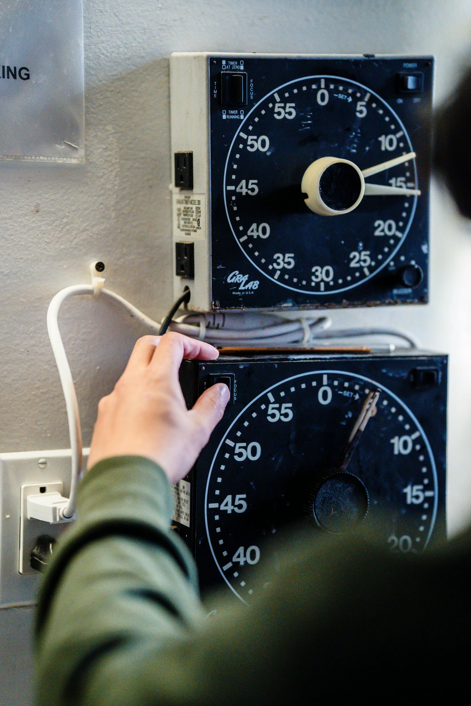 a person checking a dial on a device with an electrical wiring attached